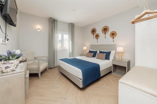 a white bedroom with a bed and a chair at AZUL in Zambujeira do Mar