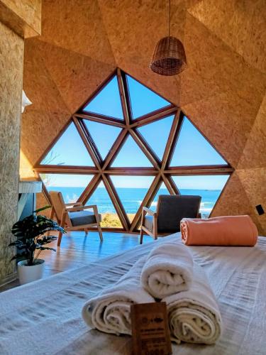 a bed in a room with a large window at Domos Mare - Glamping frente al Mar in Quequén