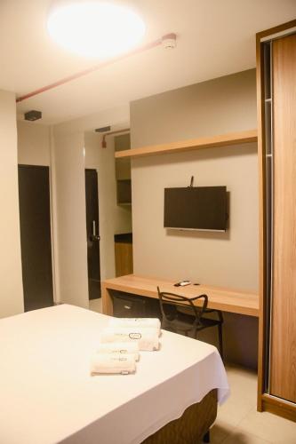 a room with a bed and a desk with a television at Sttudio One in Araxá