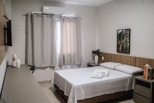 a white bedroom with a bed with two towels on it at Sttudio One in Araxá