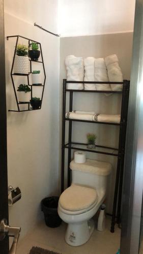 a bathroom with a toilet and a shelf with towels at Sea sight appartment in Historic Downtown in Campeche