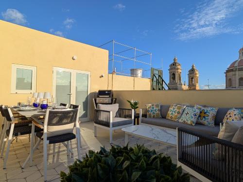 een patio met een bank en een tafel en stoelen bij Mahogany - Rooftop Views - Close to Valletta Ferry in Senglea