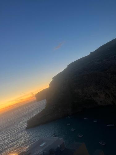 a view of the ocean at sunset with a cliff at Xlendi - Seafront 2 Bedroom Apartment, Fully Air-conditioned and equipped with all amenities in Xlendi