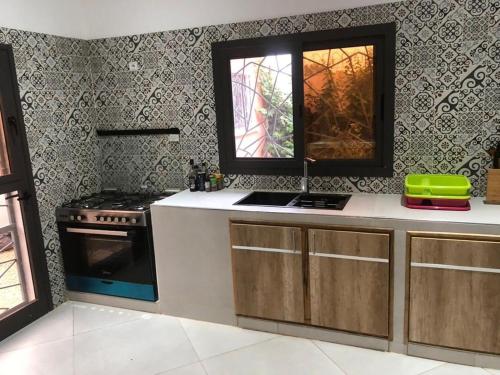 a kitchen with a stove and a sink and a window at L'Eclipse Air-Conditioned Villa with Pool in Mbour