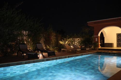 a swimming pool at night with chairs and sidx sidx sidx sidx sidx at L'Eclipse Air-Conditioned Villa with Pool in Mbour