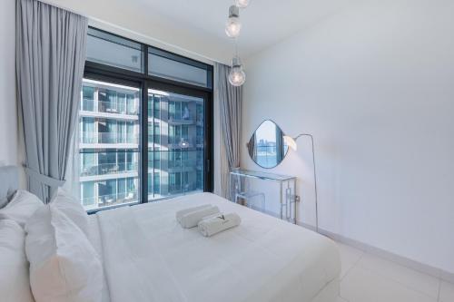 a white bedroom with a white bed and a mirror at Sea View with Private Beach Access! 3BR & Maid Rm in Dubai