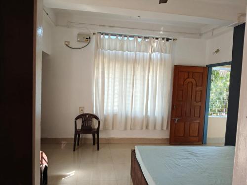 a bedroom with a bed and a chair and a window at Shimray's Minimalist Hostel in Guwahati