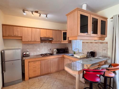 a kitchen with wooden cabinets and a white refrigerator at Montagu Villas 3min Beach Walk in Flic-en-Flac