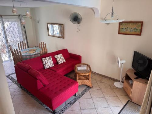 a living room with a red couch and a tv at Montagu Villas 3min Beach Walk in Flic-en-Flac