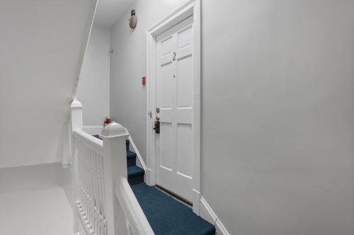 a hallway with a white door and a blue carpet at 1734 Comfort Stay, 2 Bedrooms, 2 Bath with Kitchen & Wi-Fi in Washington, D.C.