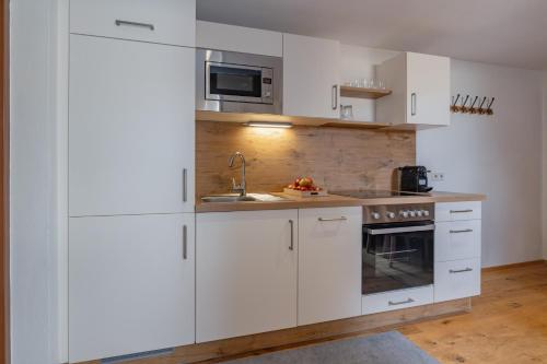 a white kitchen with white cabinets and a sink at Pleschinhof in Velden am Wörthersee