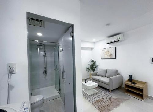 une salle de bain avec douche et toilettes et un canapé dans l'établissement Vintage Hideaway Homestay, à Hô-Chi-Minh-Ville