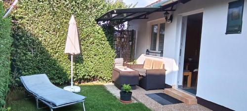 a patio with an umbrella and a chair and a table at Marianna Apartman in Gyenesdiás
