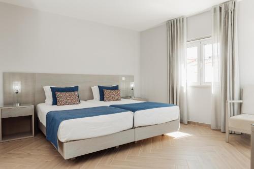 a bedroom with a large bed with blue sheets and pillows at AZUL in Zambujeira do Mar