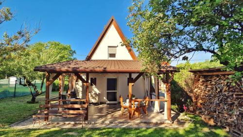 een klein huisje met een prieel en stoelen bij Velencei Odú in Velence