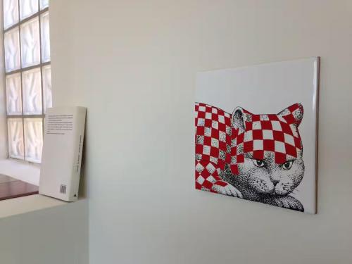 a picture of a cat with a checkered pillow next to a window at Terrazza Borromini B&B in Santo Stefano Ticino