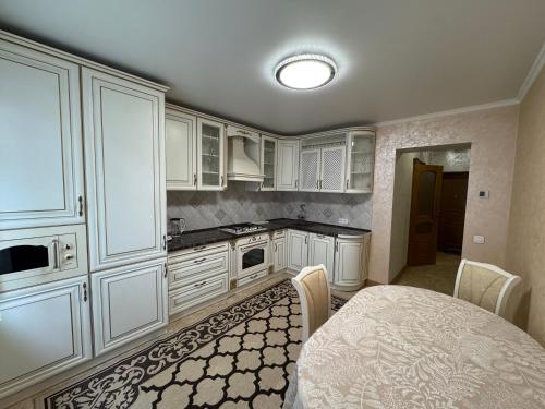 a kitchen with white cabinets and a table with chairs at 2к люкс в класичному стилі Netflix in Khmelʼnytsʼkyy
