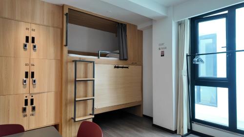 a room with a tv and wooden cabinets and a window at WeLight Hotel in Beijing