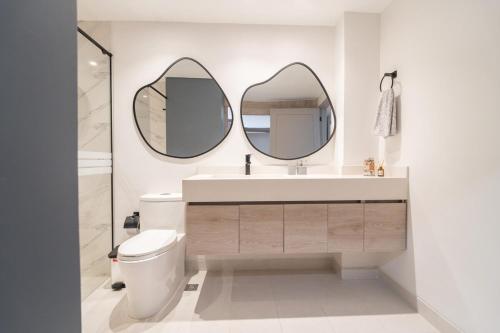 a bathroom with a toilet and two mirrors on the wall at Lux Lleras l Daily Cleaning l AC l Visitrs Allowed in Medellín