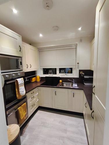 a kitchen with white cabinets and a sink at City Centre - Links Apartments - Close to Beach in Aberdeen