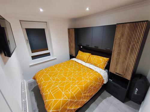 a bedroom with a yellow bed and a window at City Centre - Links Apartments - Close to Beach in Aberdeen