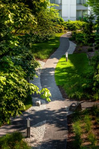 a cobblestone path in a park with a building at Hotel Warszawianka in Jachranka