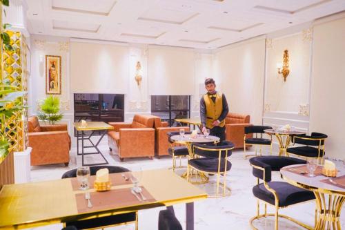 a man standing in a room with tables and chairs at Hotel Multan Suites in Multan