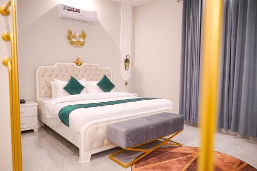a white bedroom with a white bed with green pillows at Hotel Grand Suites in Multan