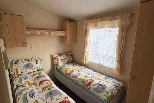 a small room with two beds and a window at Sand Le Mere Caravan in Tunstall