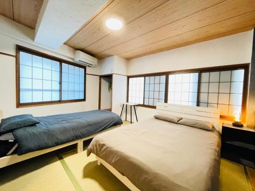a bedroom with two beds in a room with windows at Stay Narimasu - 3rooms Apartment, 4min to Narimasu station, 1min to Donki in Tokyo