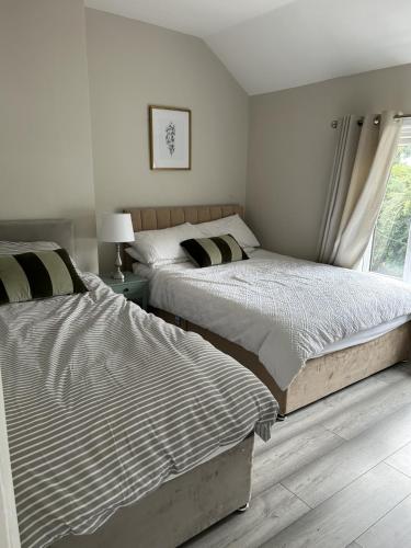 two beds in a white bedroom with a window at Luxury 3 Bed House - 10 min walk from Dartford Town Centre - Fully Refurbished in Dartford