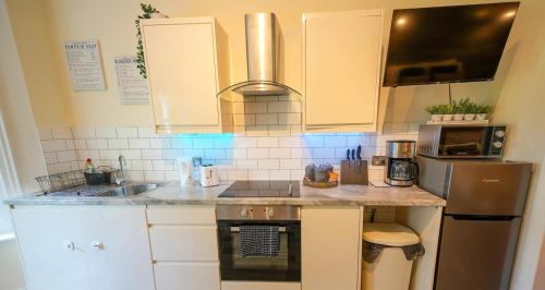 a kitchen with white cabinets and a stainless steel refrigerator at Studio with additional sofa bed - Eastbourne in Eastbourne
