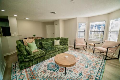 a living room with a green couch and a table at Uptown LUXE Retreat with Parking & Walk to City Center in Charlotte