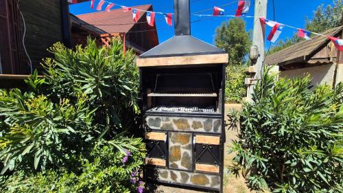 an outdoor oven in a yard with flags at Algarrobo Cabaña a 2 cuadras Playa El Canelo+Wifi in Algarrobo