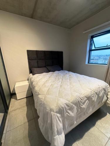 ein Schlafzimmer mit einem großen weißen Bett mit einem Fenster in der Unterkunft The luxury IN waterfall Midrand in Midrand
