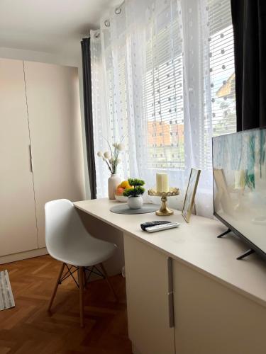 a white desk with a white chair in front of a window at Talia in Niš