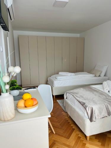a bedroom with two beds and a bowl of fruit on a table at Talia in Niš