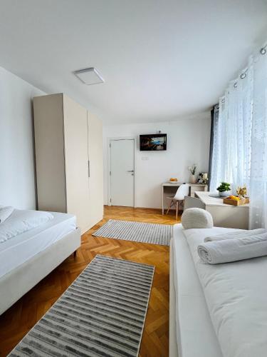 a white bedroom with two beds and a desk at Talia in Niš
