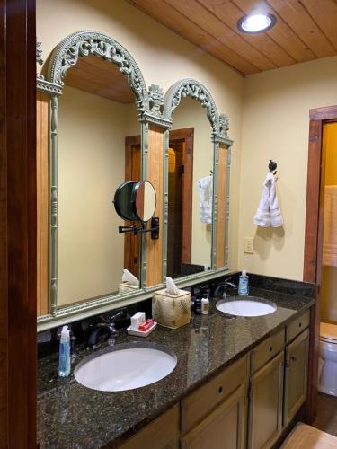 two sinks in a bathroom with two mirrors at Red Top Tree House in Highlands