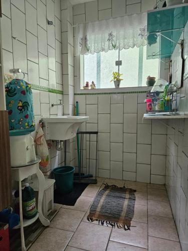 a white tiled bathroom with a sink and a window at Paraíso Ibicui in Mangaratiba