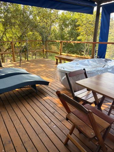 a wooden deck with a table and chairs on it at Santuário Panacéia in Piracaia