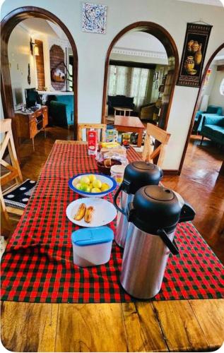 uma mesa com comida sobre uma toalha de mesa xadrez vermelha em Tropical Garden Homestay em Arusha