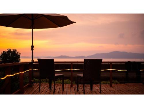 two chairs and an umbrella on a balcony with the ocean at Yunoko Umi To Yuyake - Vacation STAY 91661v in Minamata