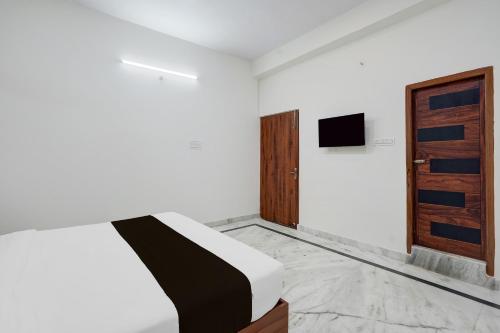 a bedroom with a bed and a wooden door at Hotel O The Skyrise Lucknow Hotel in Kākori
