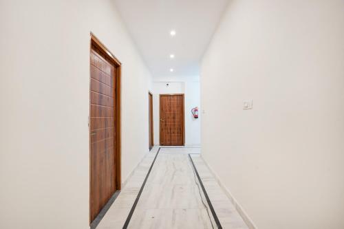 an empty hallway with a wooden door and a hallwayngth at Hotel O The Skyrise Lucknow Hotel in Kākori