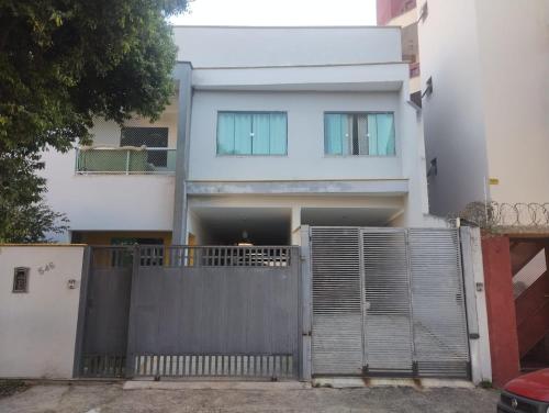 a white house with a gate and a fence at Apart 2 Ilha dos Araújos 2 quartos e completo 114 m2 in Governador Valadares