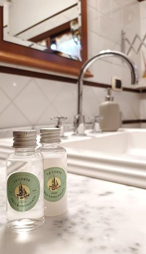 two glass bottles sitting on a counter in a bathroom at La Corte dell'Annunziata - Casa in centro con giardino in Sulmona