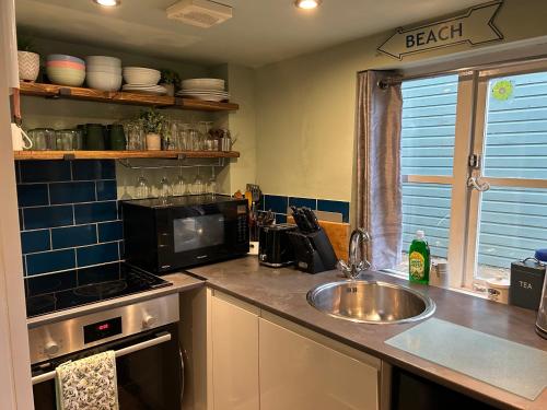a kitchen with a sink and a microwave at Fishermans Flint cottage in Sheringham