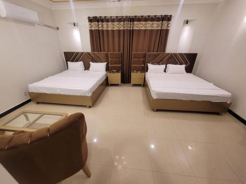 a room with two beds and a couch in it at The Bless inn Hotel in Islamabad