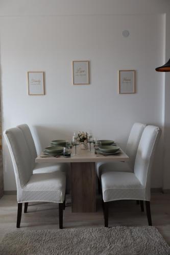 a dining room table with two white chairs and a table and chairs at Apartman TAUNUS in Kopaonik